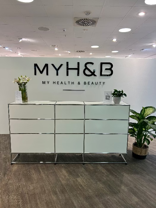 Empfangstresen von MYH&B mit Logo an der Wand und dekorativen Pflanzen
