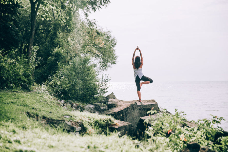 Frau beim Yoga am See – innere Balance und mentale Gesundheit durch achtsame Bewegung