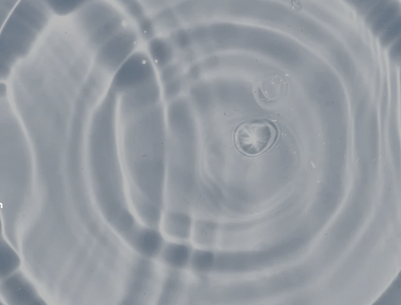 Klares Wasser mit konzentrischen Wellen und Lichtreflexionen – Symbol für Reinheit und Frische