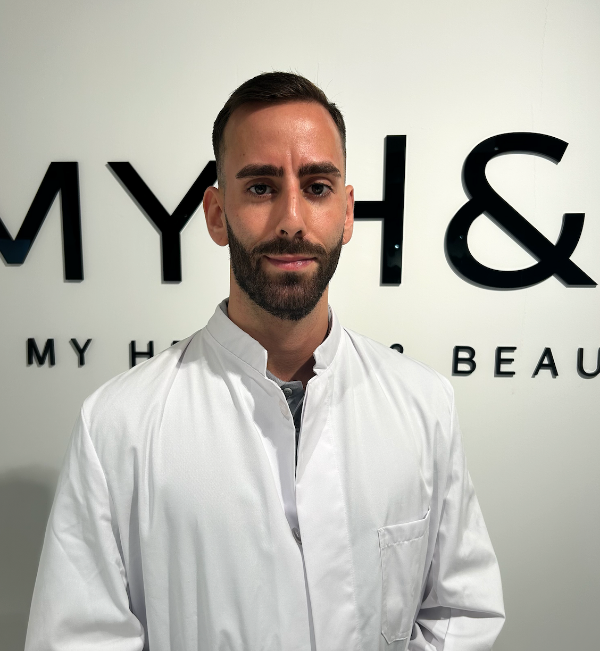 MYH&B Facharzt im weißen Kittel vor Unternehmenslogo, bereit für die Behandlung.